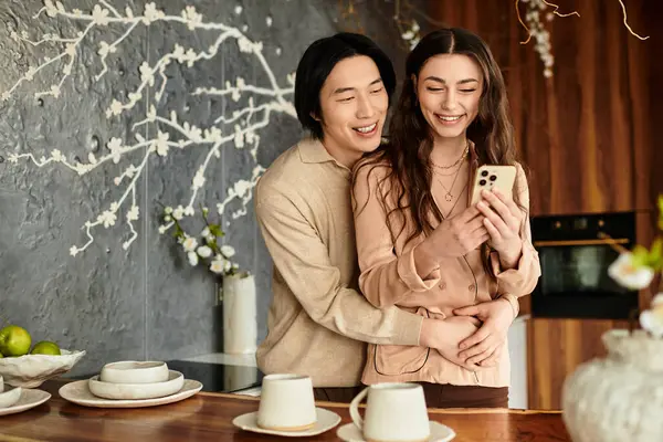 Loving couple excitedly reviews wedding plans on a smartphone in their stylish kitchen space. — Stock Photo