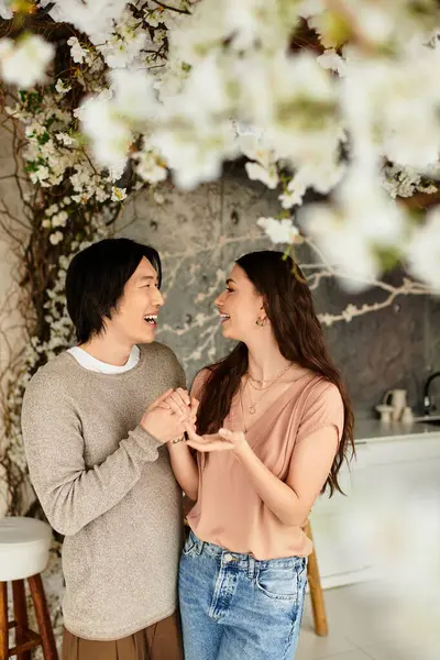 Una pareja comparte un momento tierno mientras se preparan para su boda entre flores florecientes. - foto de stock