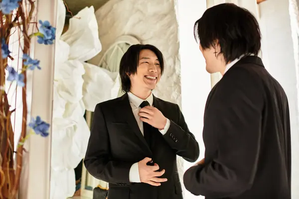 A handsome groom laughs with a friend while adjusting his tie in a stylish setting. — Stock Photo