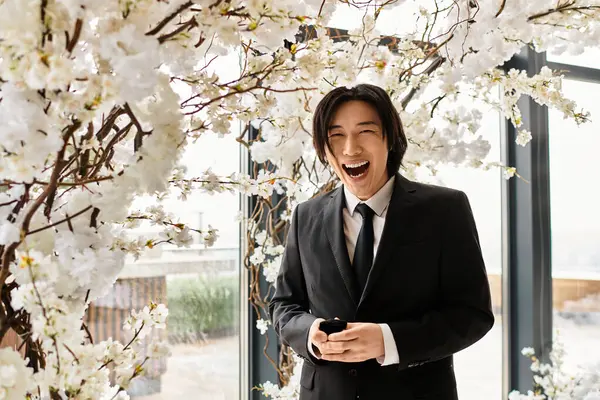 A smiling young groom stands by beautiful floral arrangements on his wedding day. — Stock Photo