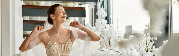 A beautiful young bride beams with happiness in a stylish venue adorned with blossoming flowers. — Stock Photo