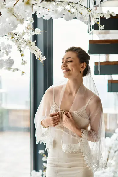 Radiant bride in delicate gown beams with happiness while adorned in beautiful floral surroundings. — Stock Photo