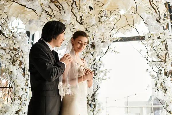 A joyful couple exchanges vows surrounded by stunning floral decorations, showcasing their love. — Stock Photo