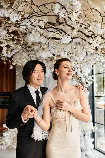 Ein glückliches Paar teilt einen liebevollen Moment bei seinem Hochzeitsempfang inmitten von Blüten. — Stockfoto