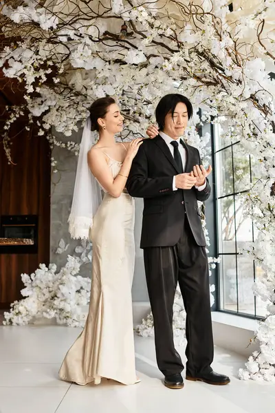 A bride adjusts her grooms attire, surrounded by stunning floral decorations. — Stock Photo