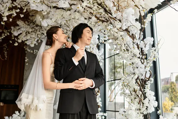Couple enjoys a tender moment during their wedding, surrounded by beautiful floral decorations. — Stock Photo