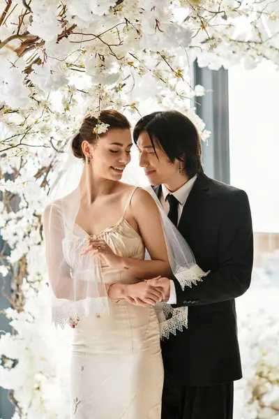 A young couple happily embraces while surrounded by exquisite floral arrangements, radiating love. — Stock Photo