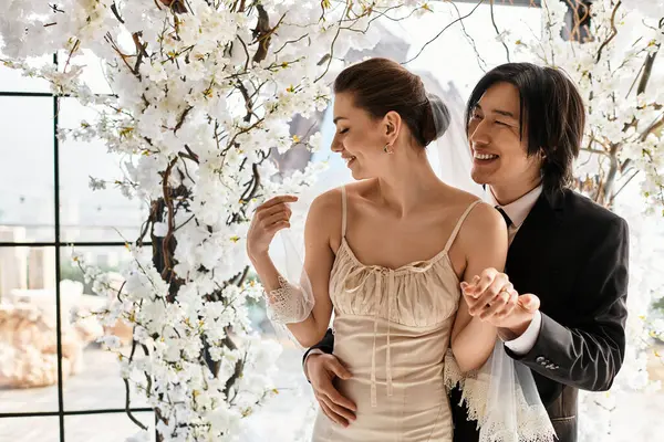 Loving couple shares a tender moment amidst beautiful blossoms, celebrating their wedding day. — Stock Photo