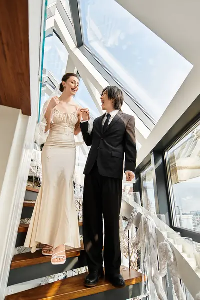 A joyful couple in wedding attire smiles at each other while walking down the stairs. — Stock Photo
