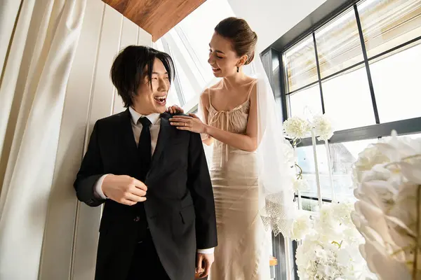 Una pareja comparte sonrisas mientras se prepara para su elegante boda en un ambiente cálido y lleno de luz. - foto de stock