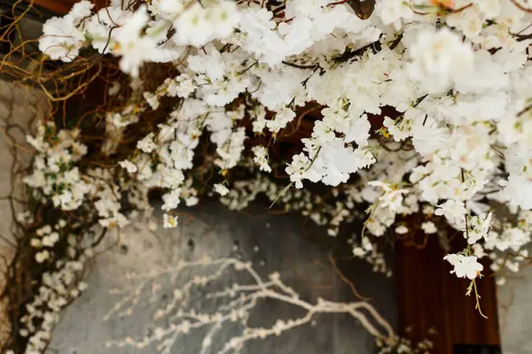 Delicate white blossoms intertwine with natural branches, enhancing a charming wedding setting. — Stock Photo