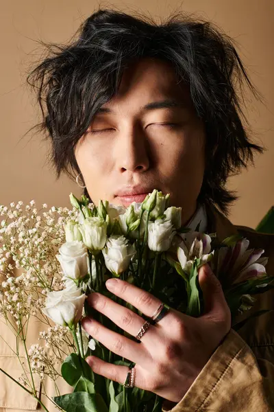 Un hombre asiático de moda posa elegantemente con flores frescas, abrazando la esencia de la primavera. - foto de stock
