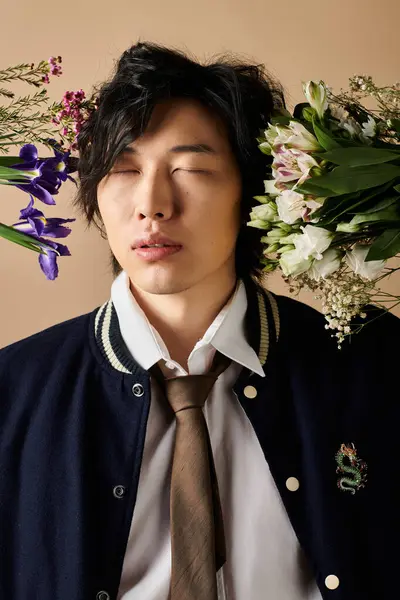 Un hombre asiático con estilo capta la atención en un estudio temático de primavera con flores vibrantes. - foto de stock