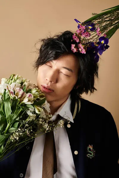 Un hombre asiático de moda posa con flores, mostrando vibraciones de primavera en un entorno de estudio. - foto de stock
