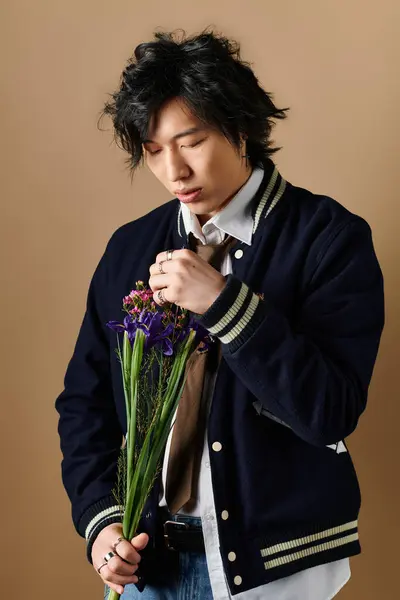 Asian man showcases spring fashion trends with a floral bouquet in a chic studio setting. — Stock Photo