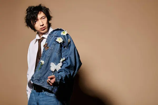 Un homme asiatique présente un look printemps unique dans un studio chic, mettant en valeur le style denim floral. — Photo de stock