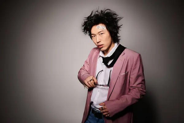 An asian man confidently poses in chic attire, exuding style in a vibrant studio setting. — Stock Photo