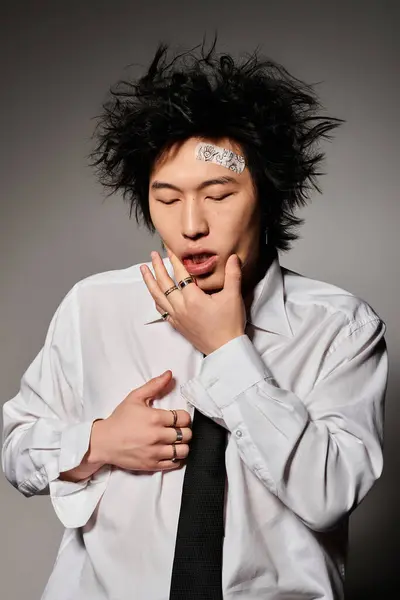 An Asian man feeling hurt after fight showcases his style with a unique hairstyle and fashionable spring outfit. — Stock Photo
