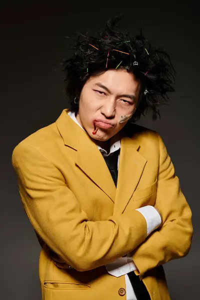Un hombre asiático elegante con sangre en la cara hace alarde de un aspecto audaz con accesorios para el cabello vibrante esta primavera. - foto de stock