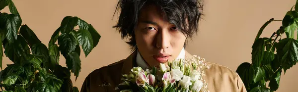 Un homme asiatique exhibe sa mode printanière dans un studio chic, entouré de verdure et de fleurs, bannière — Photo de stock