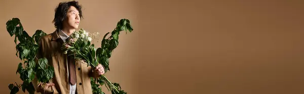 Un uomo asiatico mette in mostra abbigliamento primaverile alla moda, circondato dal verde e vivaci fiori. — Foto stock