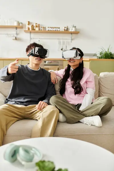 A young couple sits on their couch, immersed in a virtual reality experience, sharing excitement. — Stock Photo