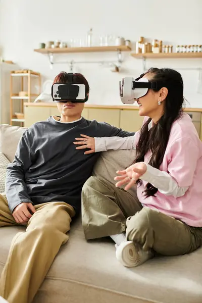In a warm living room, a young Asian couple shares an exciting virtual reality experience. — Stock Photo