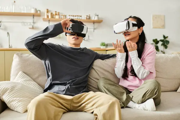 Young couple relaxes on a sofa, enjoying a virtual reality experience together. — Stock Photo