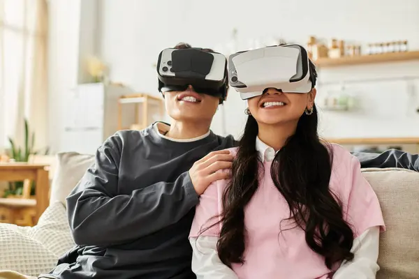 A young asian couple experiences virtual reality, smiling and sharing laughter while at home. — Stock Photo