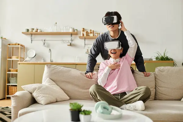 A joyful young couple experiences virtual reality while relaxing on their cozy couch together. — Stock Photo