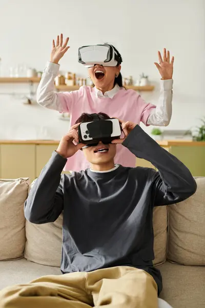 A young couple at home engages in virtual reality entertainment, sharing joy and laughter. — Stock Photo