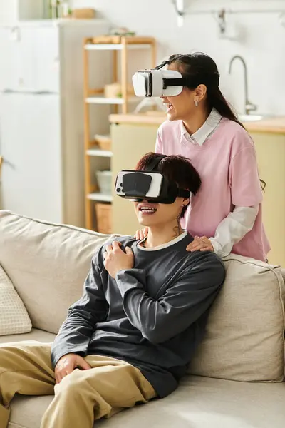A young couple experiences immersive technology while relaxing on a comfy couch. — Stock Photo