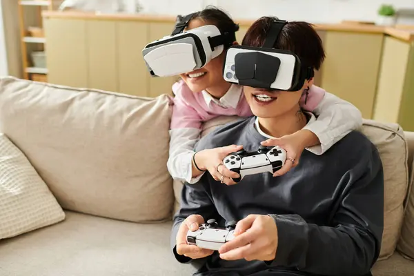 Una joven pareja se involucra alegremente en juegos de realidad virtual en un cómodo sofá, intercambiando sonrisas. - foto de stock