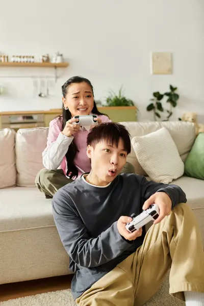 A couple sits on a couch engaged in an exciting gaming session at home, sharing laughter and energy. — Stock Photo