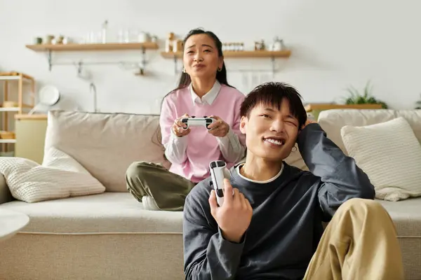 A young couple sits comfortably in their living room, engaged in a playful gaming session. — Stock Photo