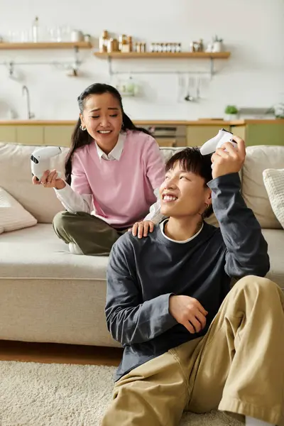 A young asian couple shares laughter and joy while playing games at home, creating memories. — Stock Photo