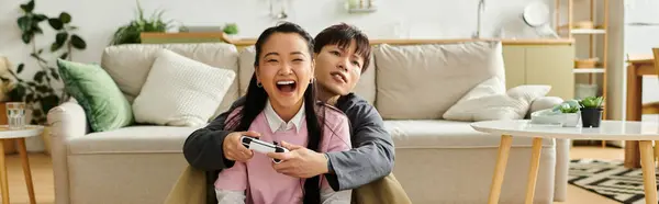 Ein junges asiatisches Paar genießt seine Zeit zu Hause und teilt das Lachen beim gemeinsamen Spielen von Videospielen, Banner — Stockfoto