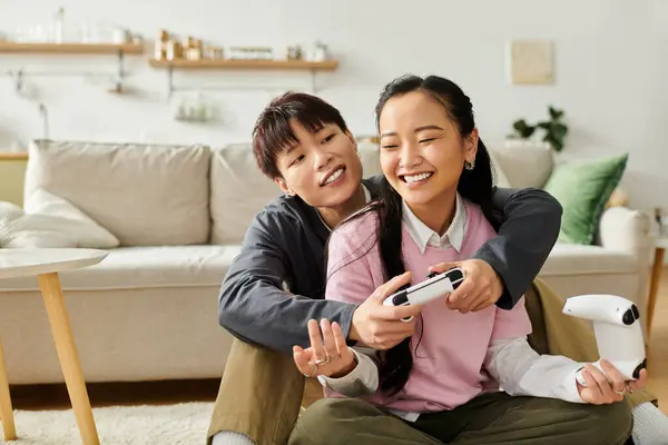 Ein junges asiatisches Paar spielt zu Hause fröhlich Videospiele zusammen, lächelt und lacht. — Stockfoto