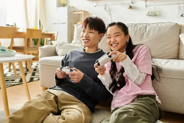Ein fröhliches junges asiatisches Paar spielt auf dem Boden, umgeben von einem hellen, einladenden Wohnraum. — Stockfoto