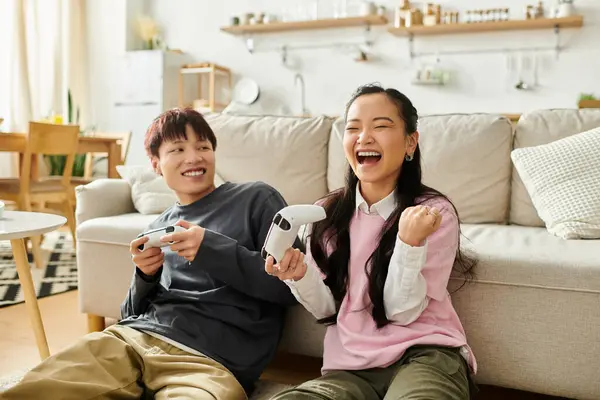 Una giovane coppia asiatica condivide risate e divertimento mentre gioca su un comodo divano a casa. — Foto stock