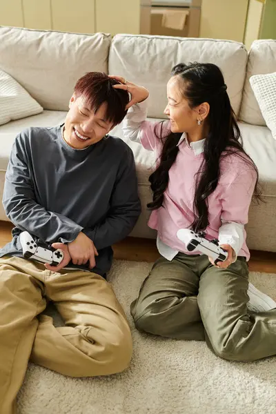 Ein junges asiatisches Paar spielt gerne auf dem Fußboden und teilt Lachen und verspielte Momente zu Hause. — Stockfoto