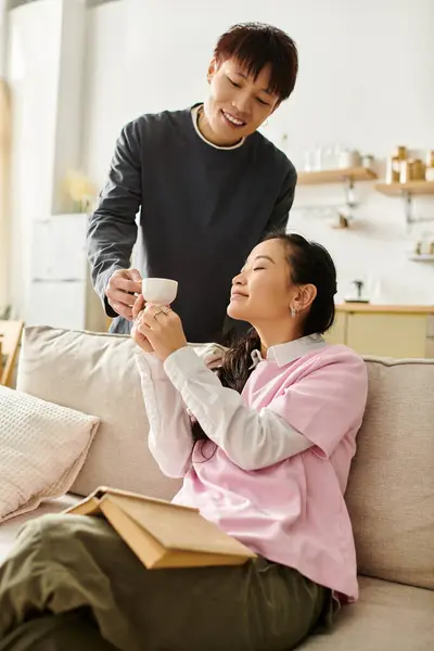 A young couple cherishes a tender moment at home while sharing a warm drink and smiles. — Stock Photo