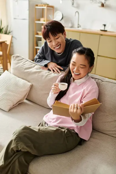 In a warm and inviting home, a young couple shares laughter while enjoying a book and coffee. — Stock Photo