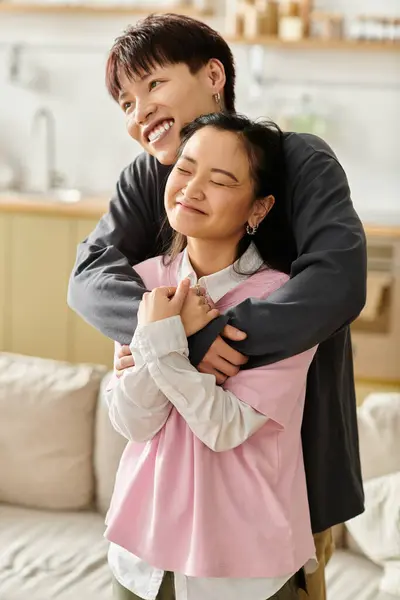 A young asian couple embraces warmly, sharing a joyful and tender moment in their home. — Stock Photo