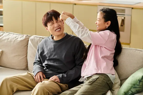 A young couple enjoys a lighthearted moment on their couch, smiling and playfully interacting. — Stock Photo