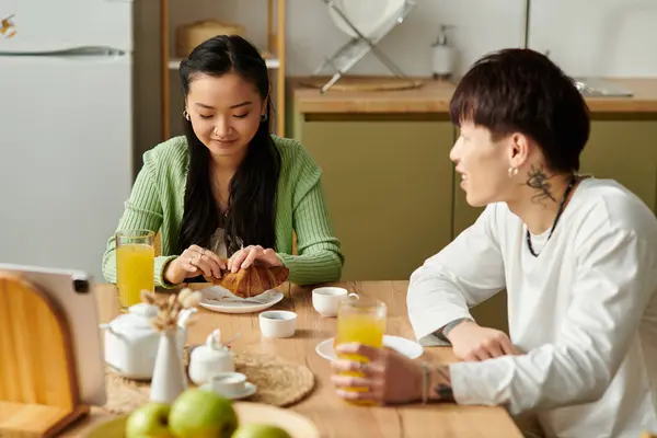 A young Asian couple enjoys breakfast at their cozy kitchen table, filled with joy. — Stock Photo