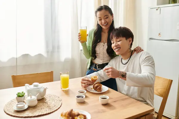 A young Asian couple enjoys a cozy breakfast together, sharing laughter and food. — Stock Photo