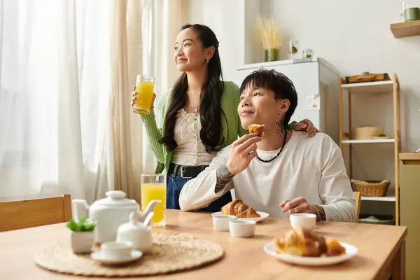 Young couple shares joyful moments at home, savoring breakfast and drinks together. — Stock Photo