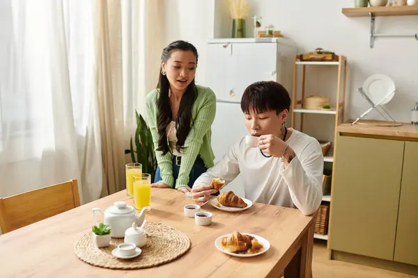 A young couple enjoys a delightful breakfast together, savoring pastries and drinks in their home. — Stock Photo