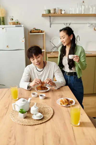 A young couple shares a delightful breakfast with coffee and pastries in their cozy kitchen. — Stock Photo